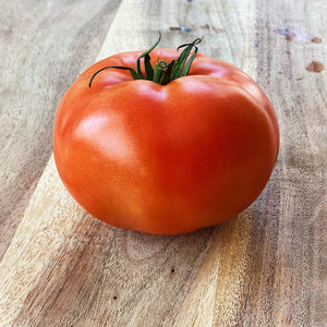 single beefsteak tomato on a wooden board