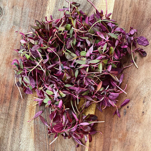red amaranth leaves on a wooden board
