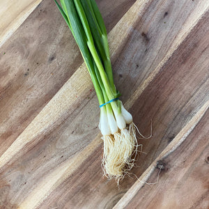 bunch of fresh green spring onions on a wooden board