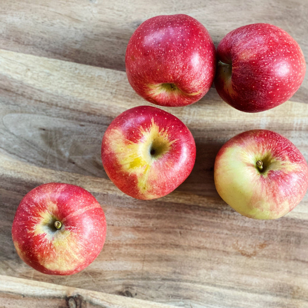 5 Royal Gala apples on a wooden board
