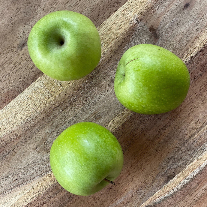 crisp fresh green granny smith apples on a wooden board