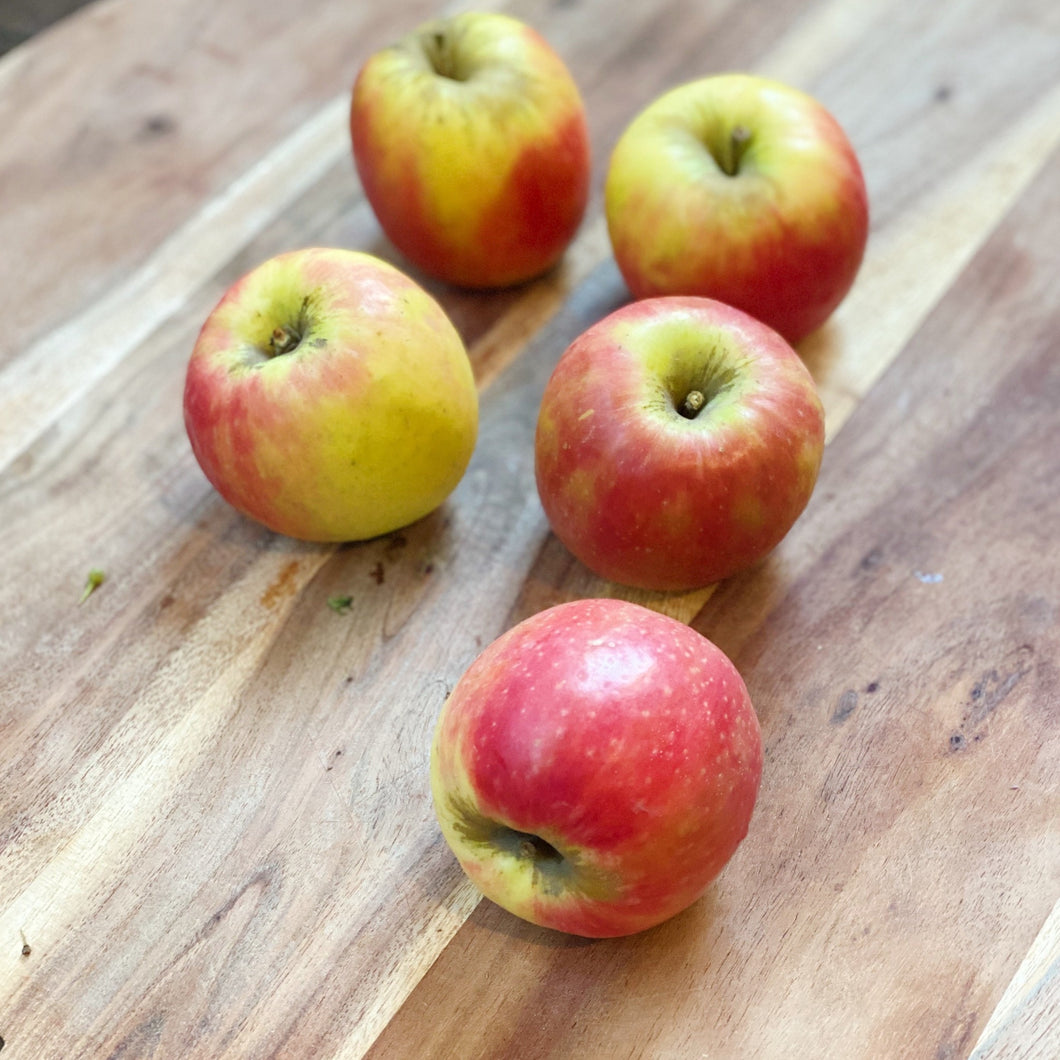 5 pink lady apples on a wooden board