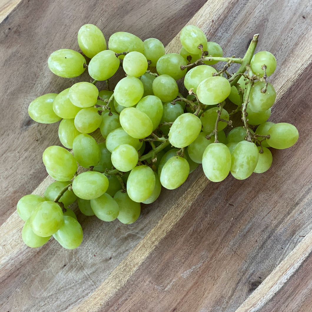 bunch of green grapes on a wooden board