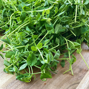 fresh pea shoots on a wooden board