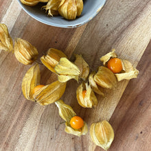 Load image into Gallery viewer, physalis on a wooden board with a glimpse of a bowl with physalis above it

