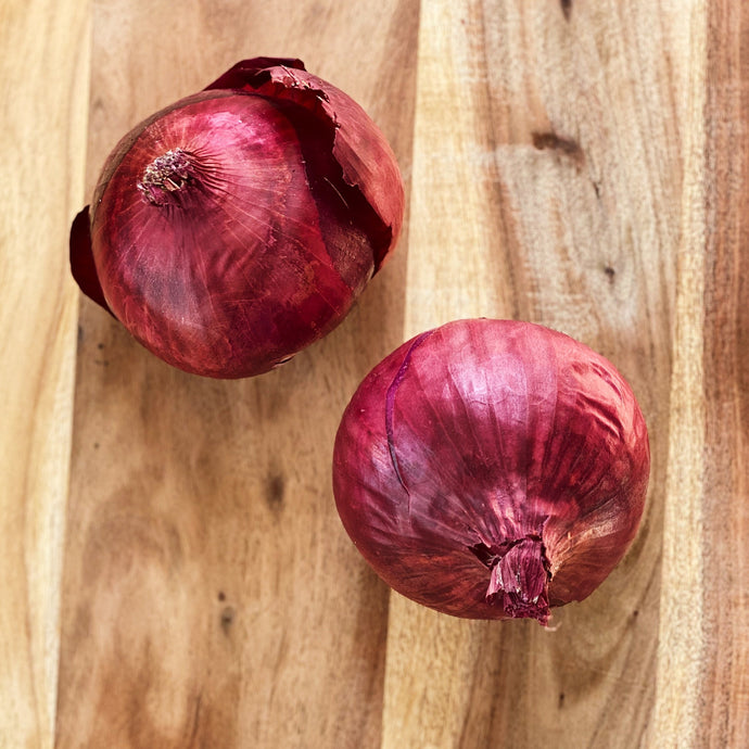raw red onions on a wooden board