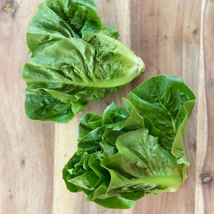 2 little gem lettuces on a wooden board