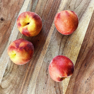 4 peaches on a wooden board