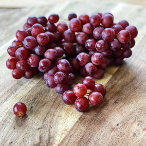 bunch of purple red grapes on a wooden board