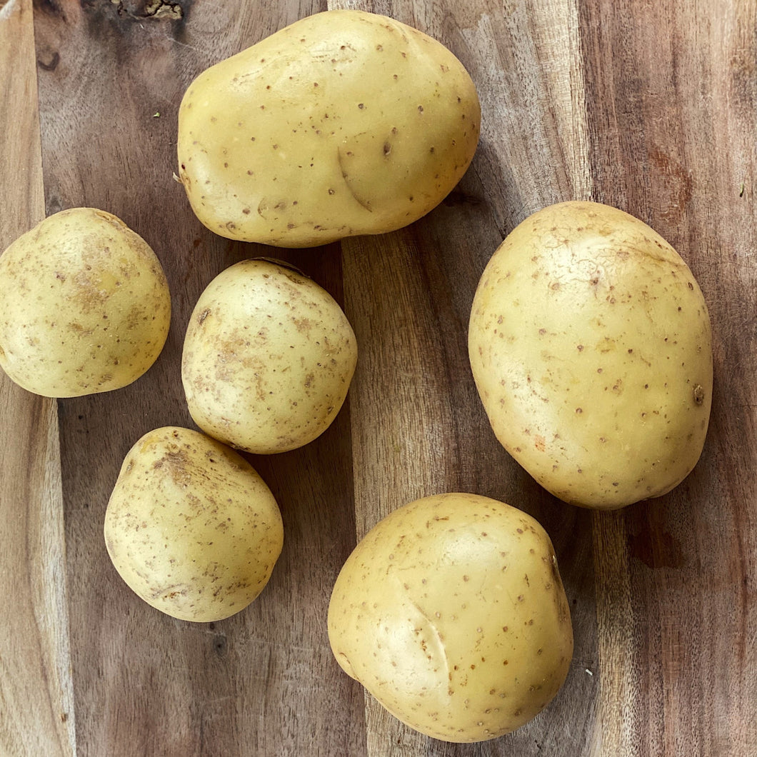 6 loose potatoes on a wooden board