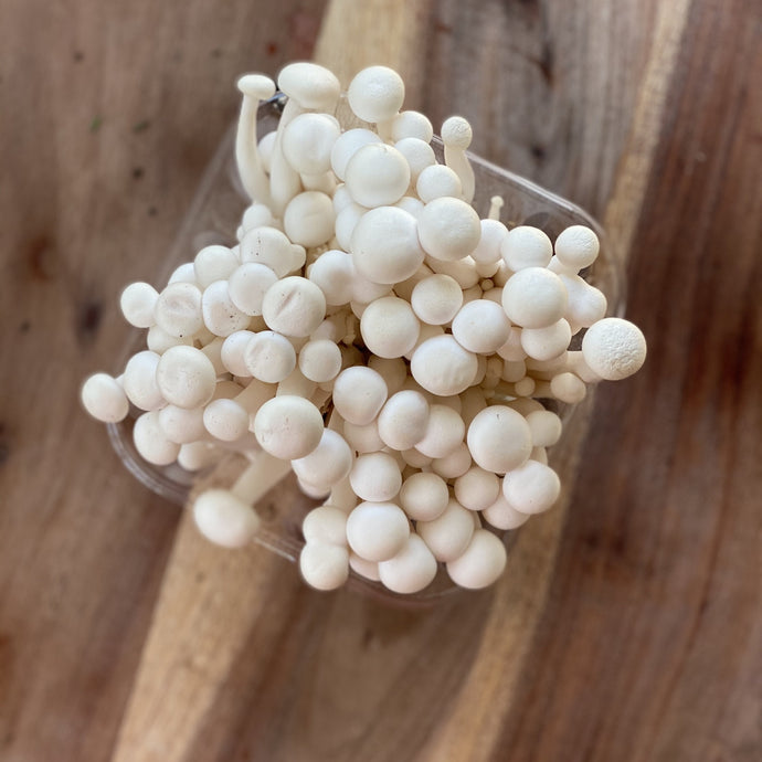white beech mushrooms in a punnet on a wooden board