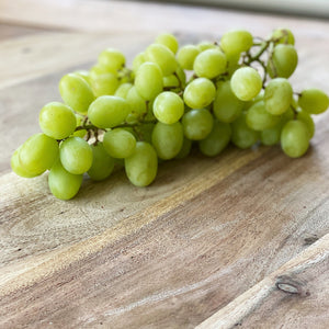 bunch of green grapes on a wooden board