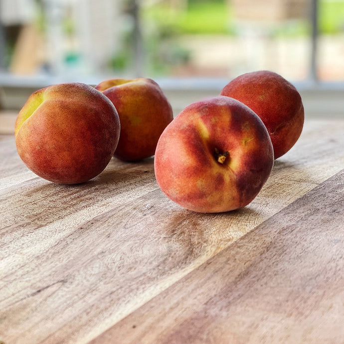 4 peaches on a wooden board