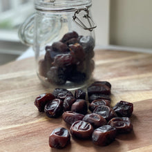 Load image into Gallery viewer, persian dates in a glass jar and loose on a wooden board
