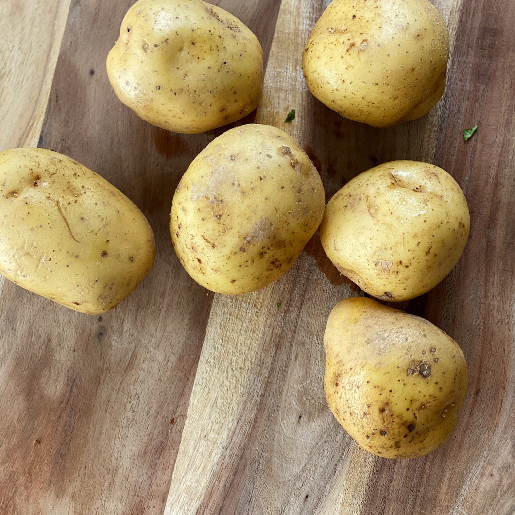 6 large potatoes on a wooden board