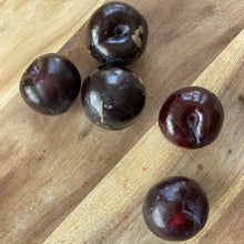 Load image into Gallery viewer, 5 glossy purple plums on a wooden board
