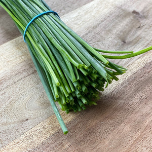 bunch of fresh chives on a wooden board