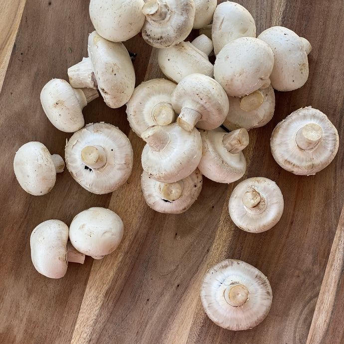collection of white cup mushrooms on a wooden board