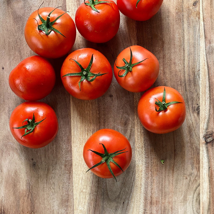 9 fresh red tomatoes on a wooden board