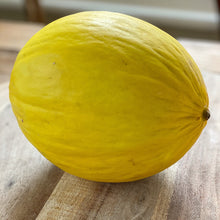 Load image into Gallery viewer, whole yellow honeydew melon on a wooden board
