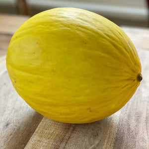 whole yellow honeydew melon on a wooden board