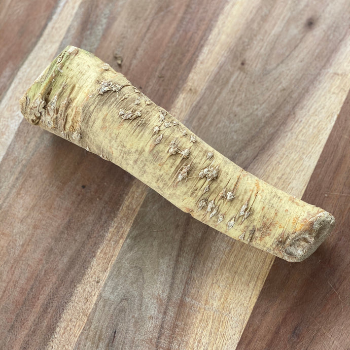 stick of fresh horseradish on a wooden board