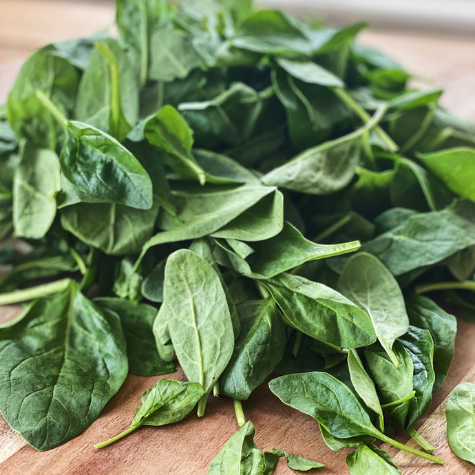 fresh baby spinach on a wooden board