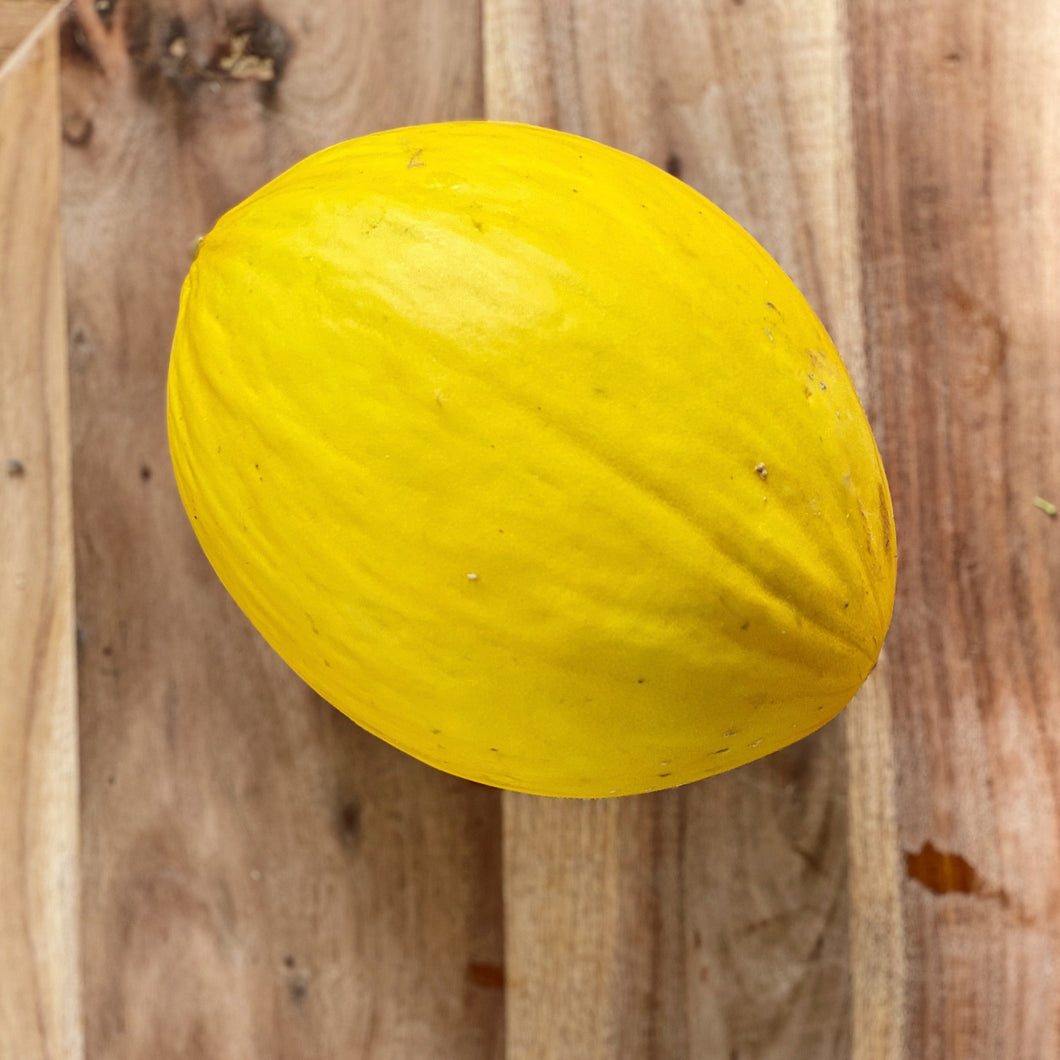 yellow whole honeydew melon on a wooden board