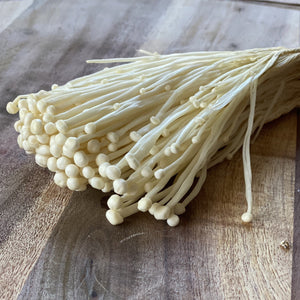 enoki mushrooms on a wooden board