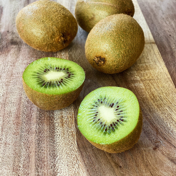 4 kiwi fruits on a wooden board one cut open