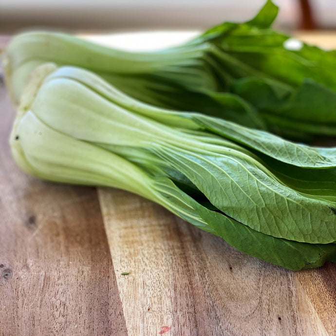 2 bulbs of pak choi on a wooden board