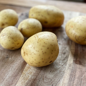 6 loose potatoes on a wooden board