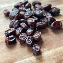 Load image into Gallery viewer, loose persian dates on a wooden board
