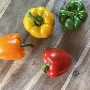 green yellow orange red peppers on a wooden board